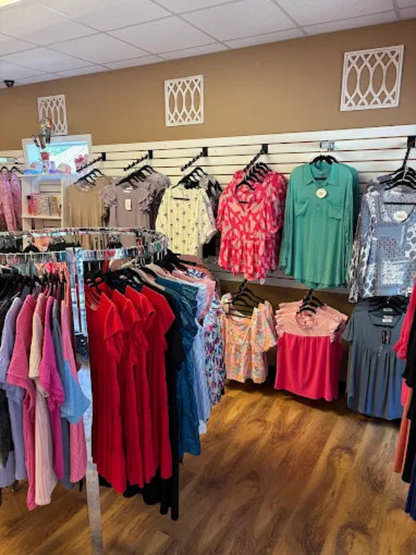 Display of colorful women's clothing in a store with wooden flooring.