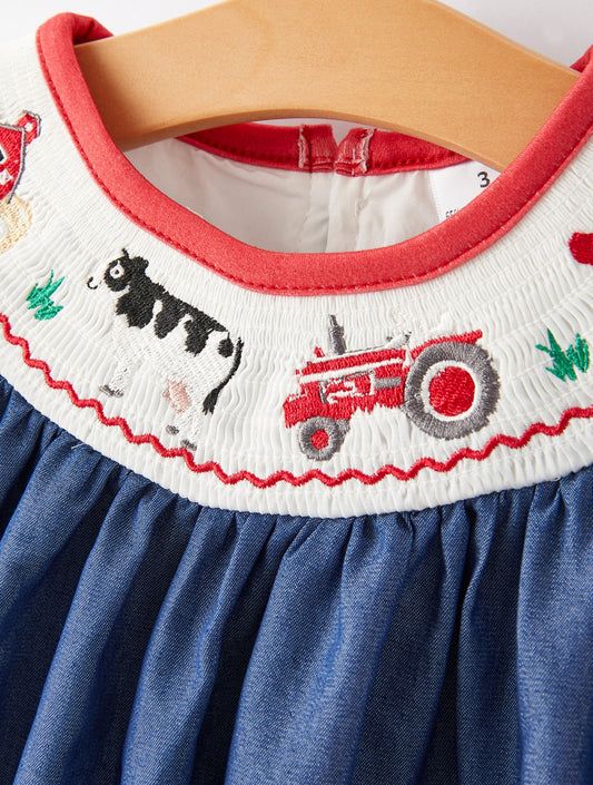 Children's dress with embroidered collar featuring a cow and tractor design on a hanger.